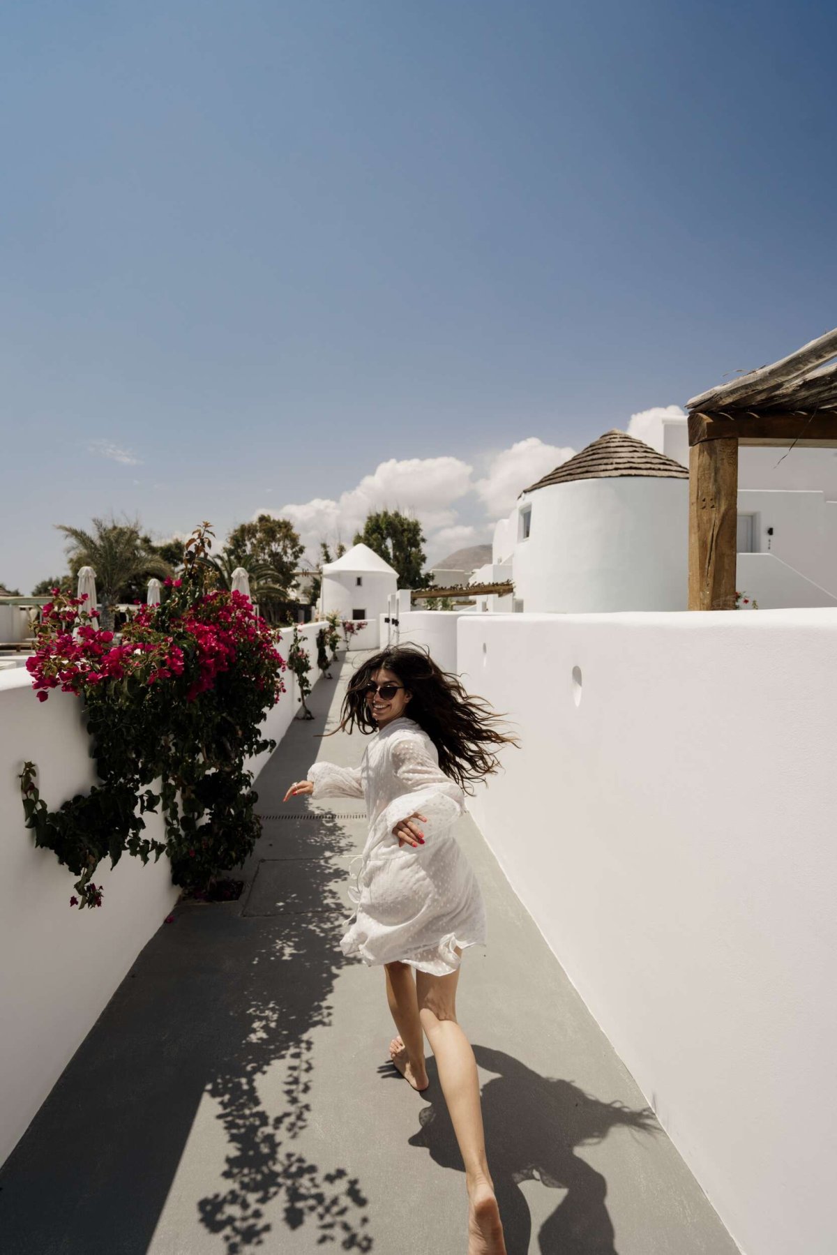 Running barefoot through whitewashed paths lined with bright bougainvillea — the joy of island life captured under a perfect summer sky