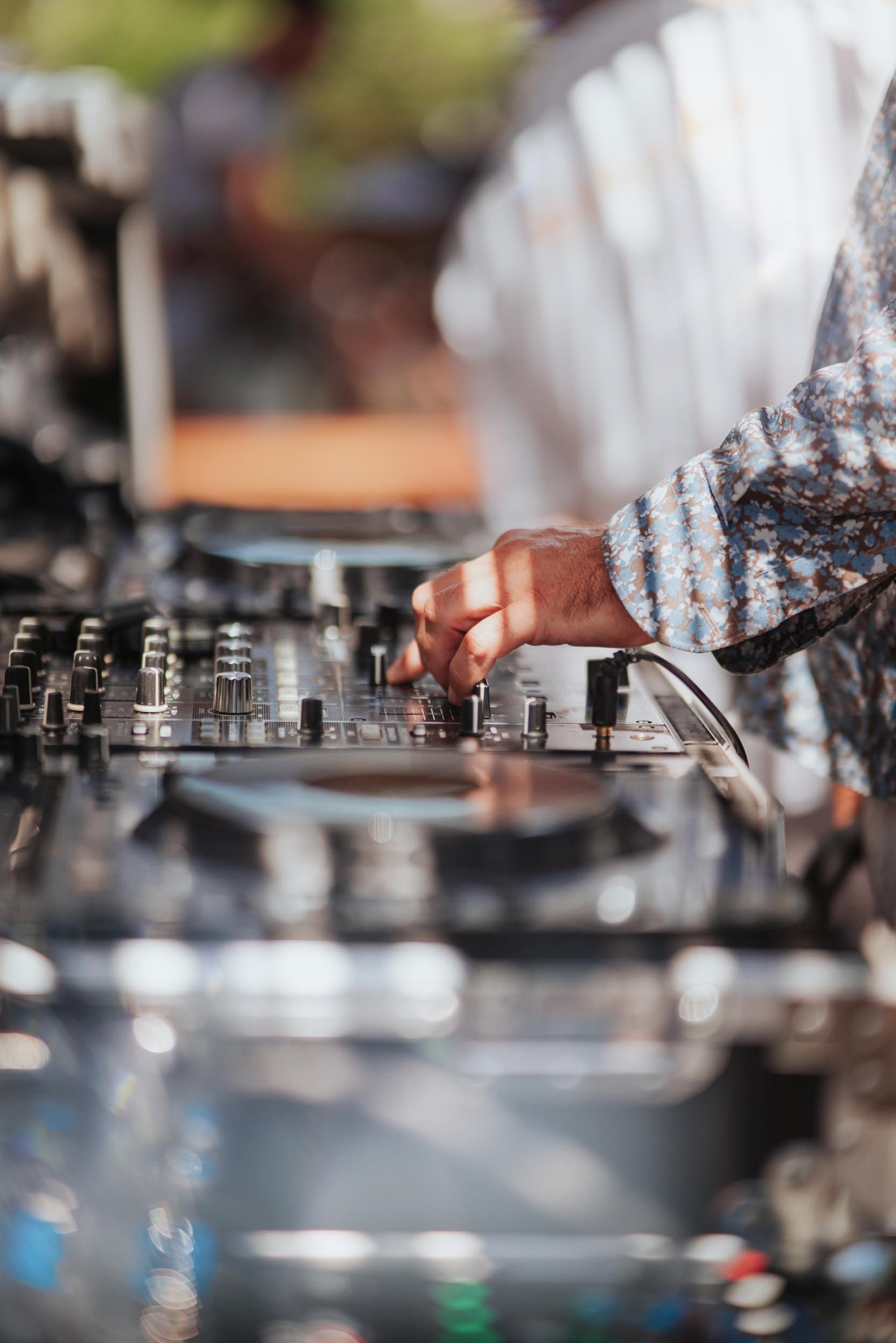 Close up or DJ mixing decks and a persons hand adjusting the dials