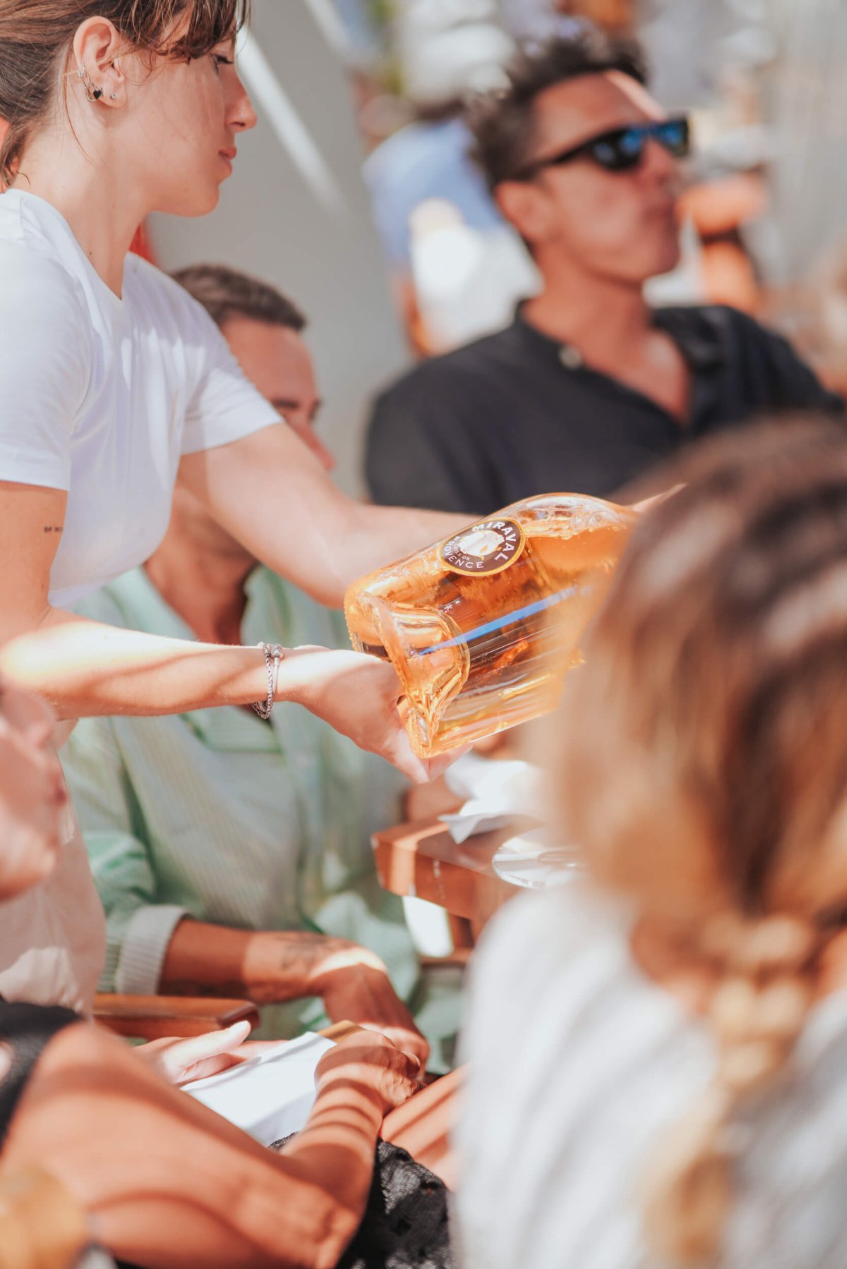 Waiter pouring wine with guests drinking in the background