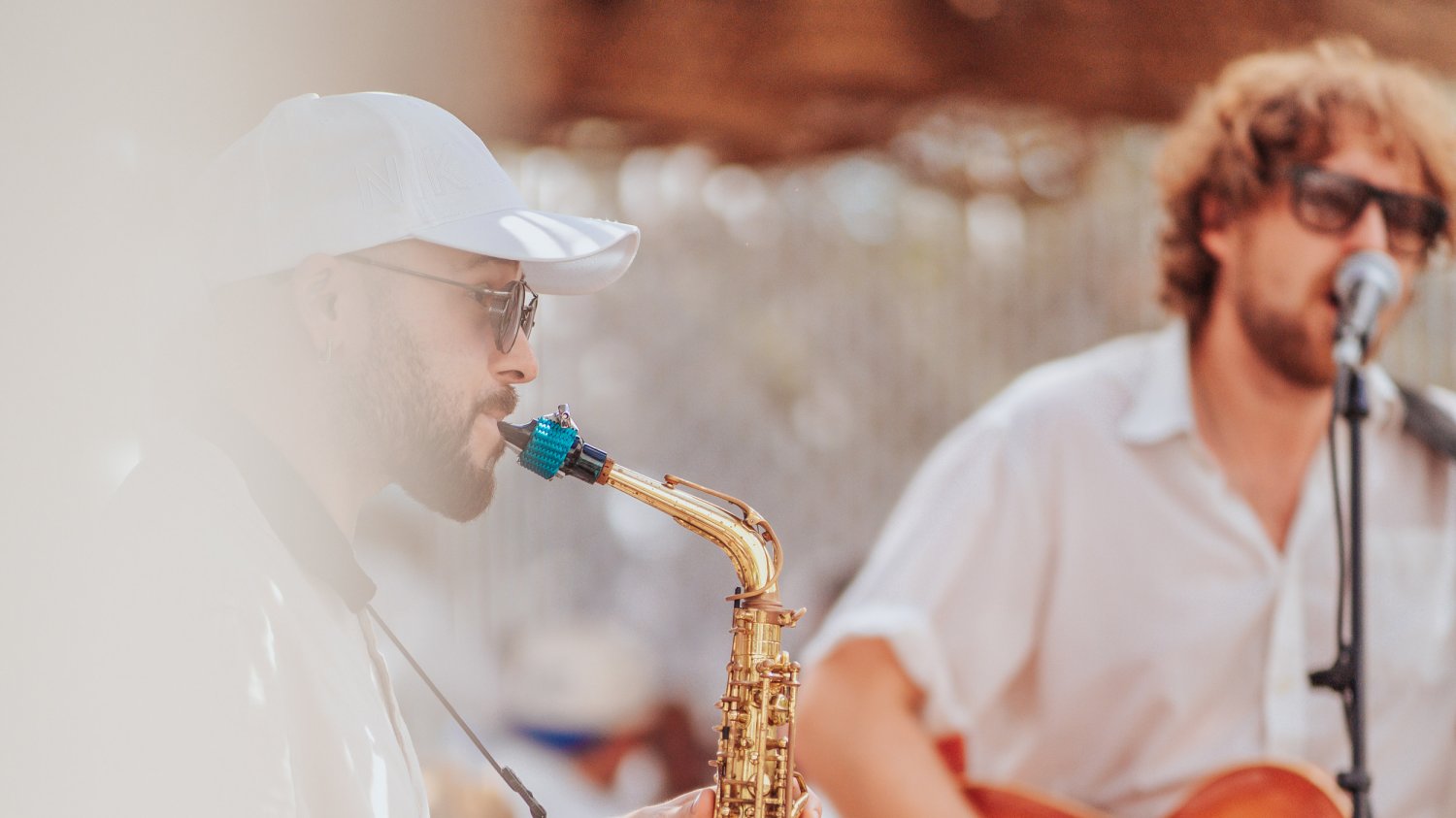 two men, one playing the saxophone and one playing the guitar while singing