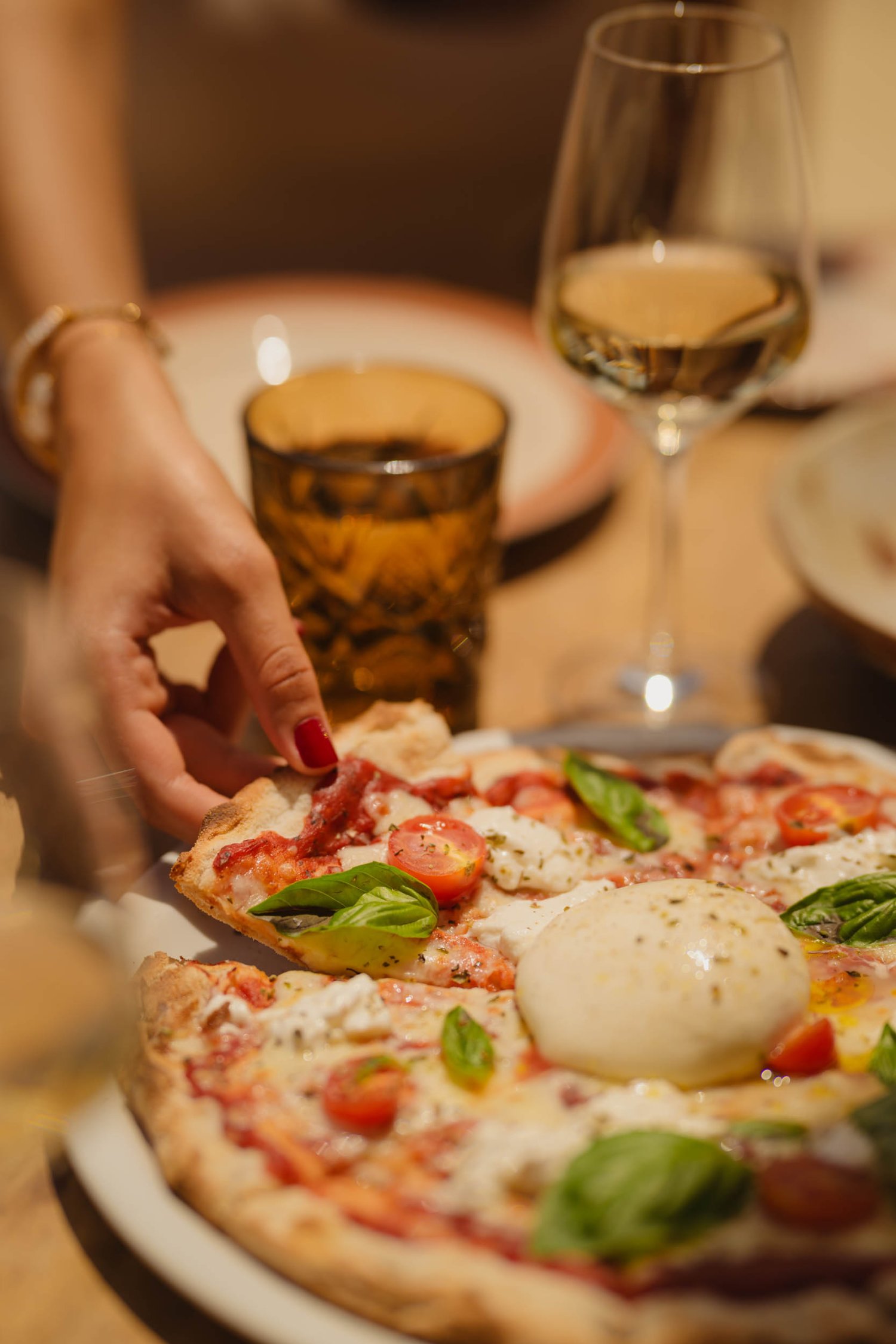 A lady taking a slice of margherita pizza