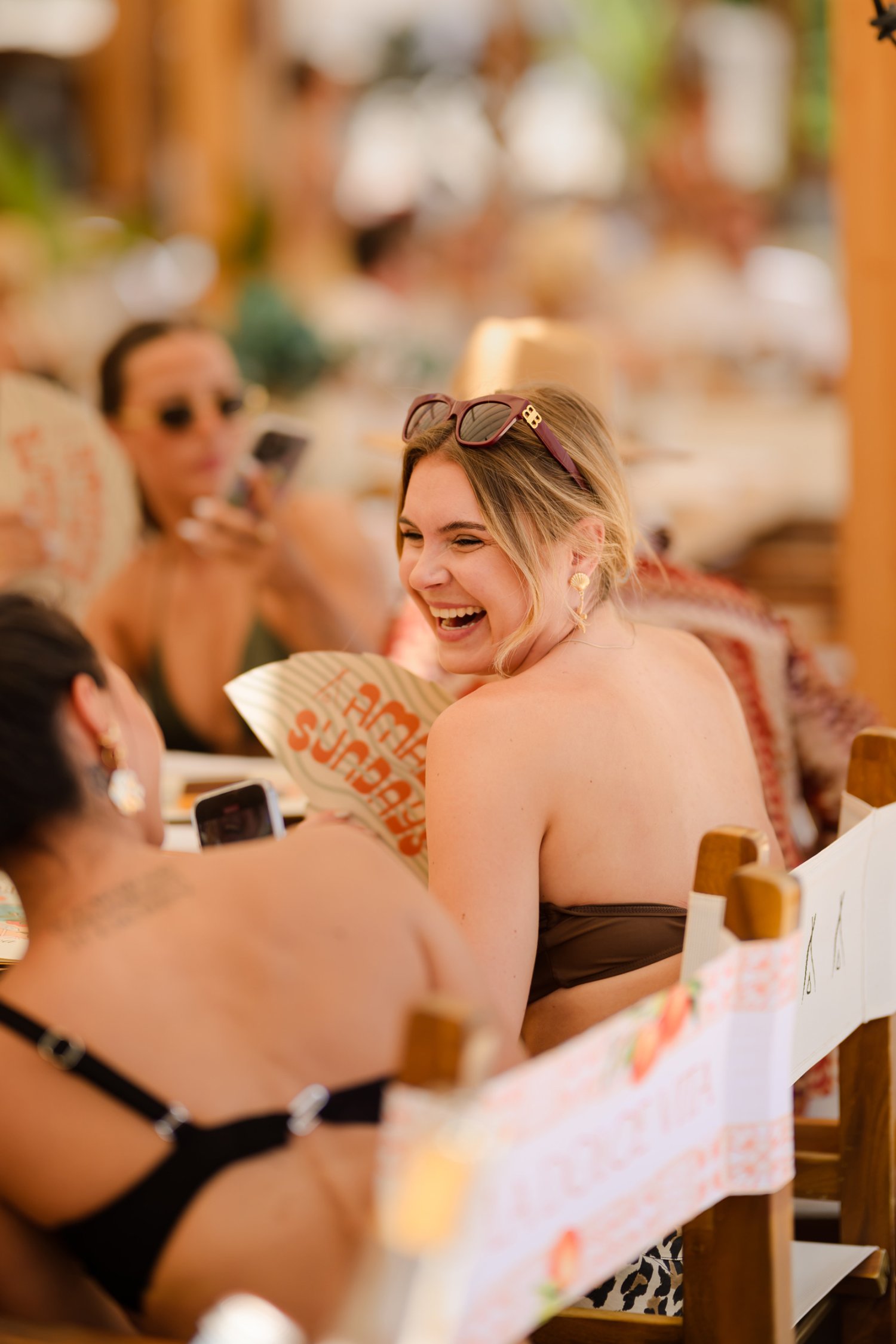 two women laughing sitting down outside, looking a t each other