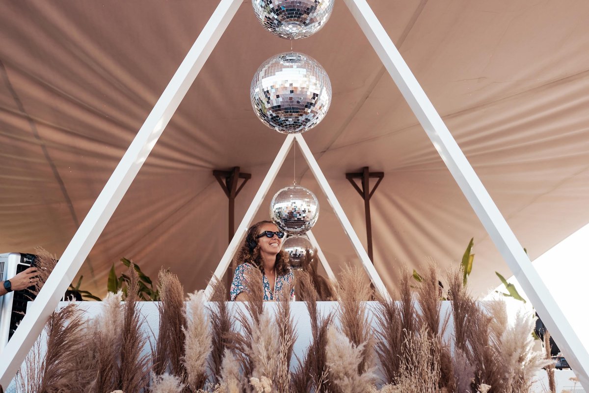 A women DJ'ing on stage with disco balls above