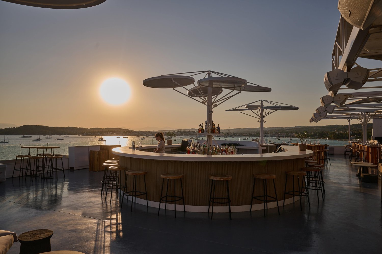 A luxurious rooftop bar with elegant seating, offering stunning sea views and a vibrant atmosphere at sunset