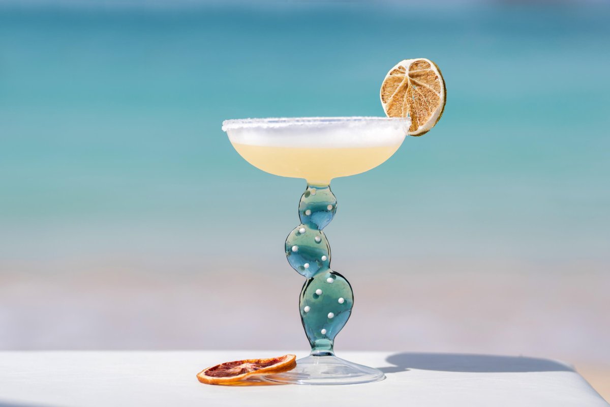 Wide angle shot of a margarita in focus with the sand and sea out of focus in the background