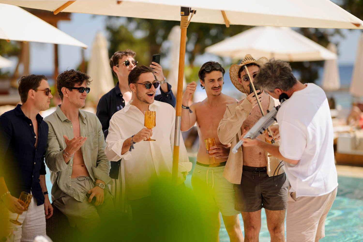 group of men drinking and listening to a man playing the violin