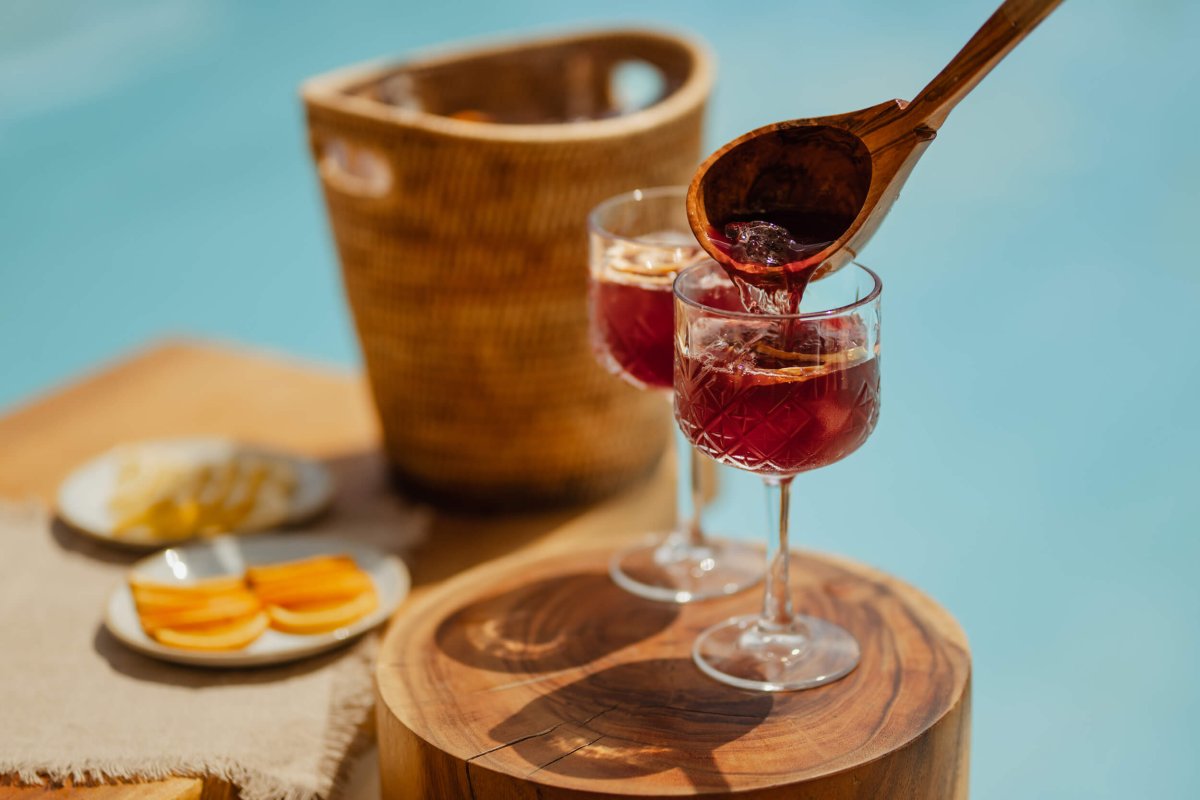 Sangria being poured into a glass with a wooden spoon