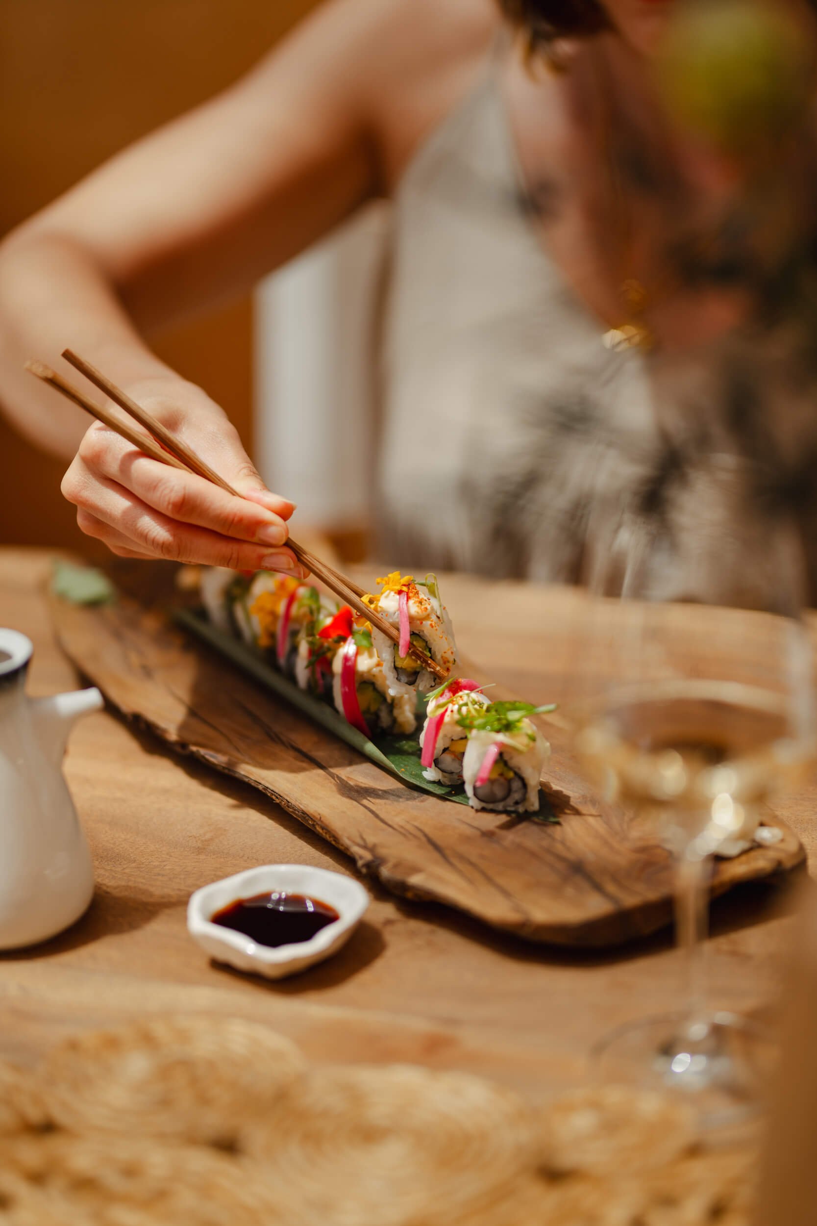 Close up of a woman picking up sushi with chop sticks
