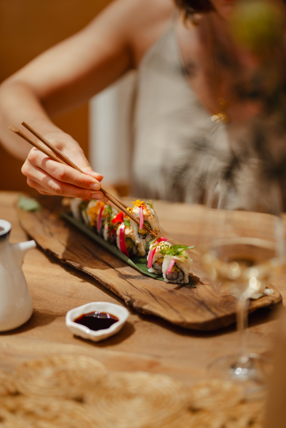 A women eating a sushi platter with chopsticks
