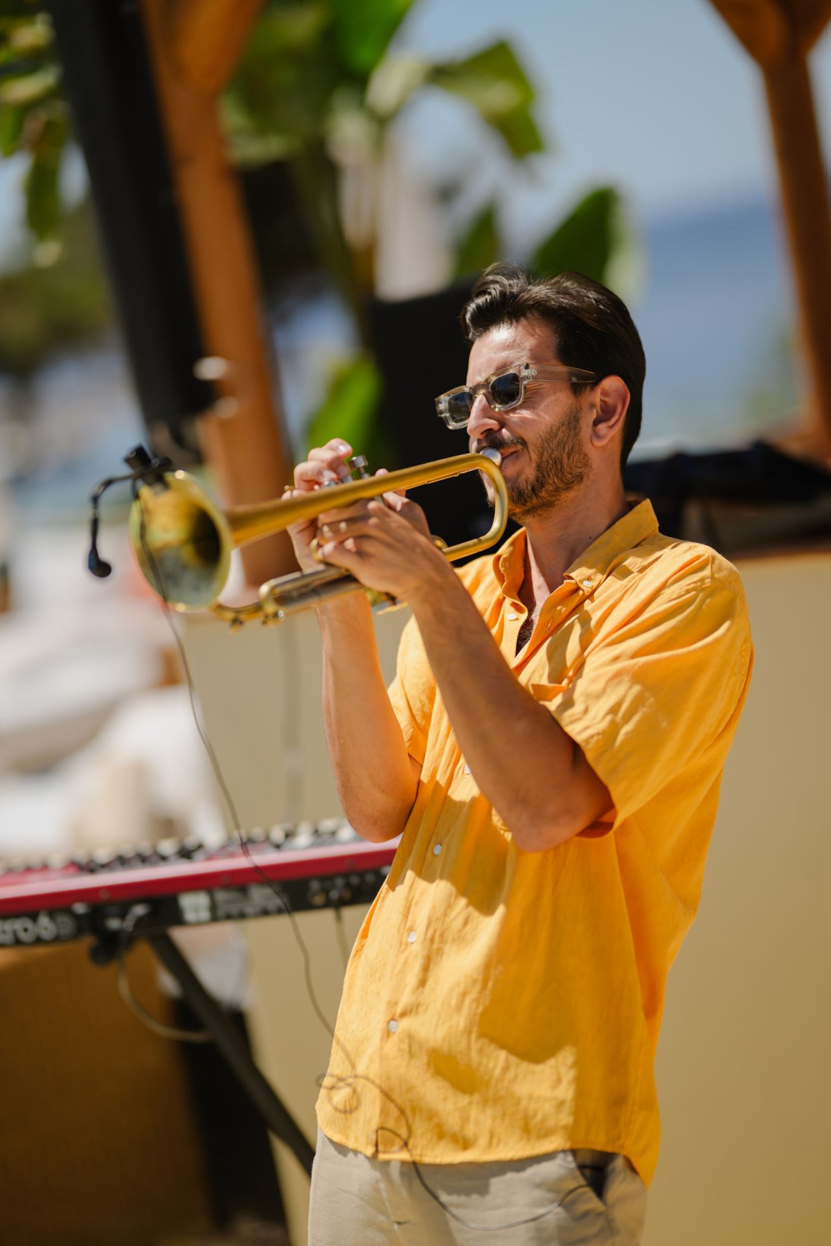 A man in a yellow shirt playing the trumpet