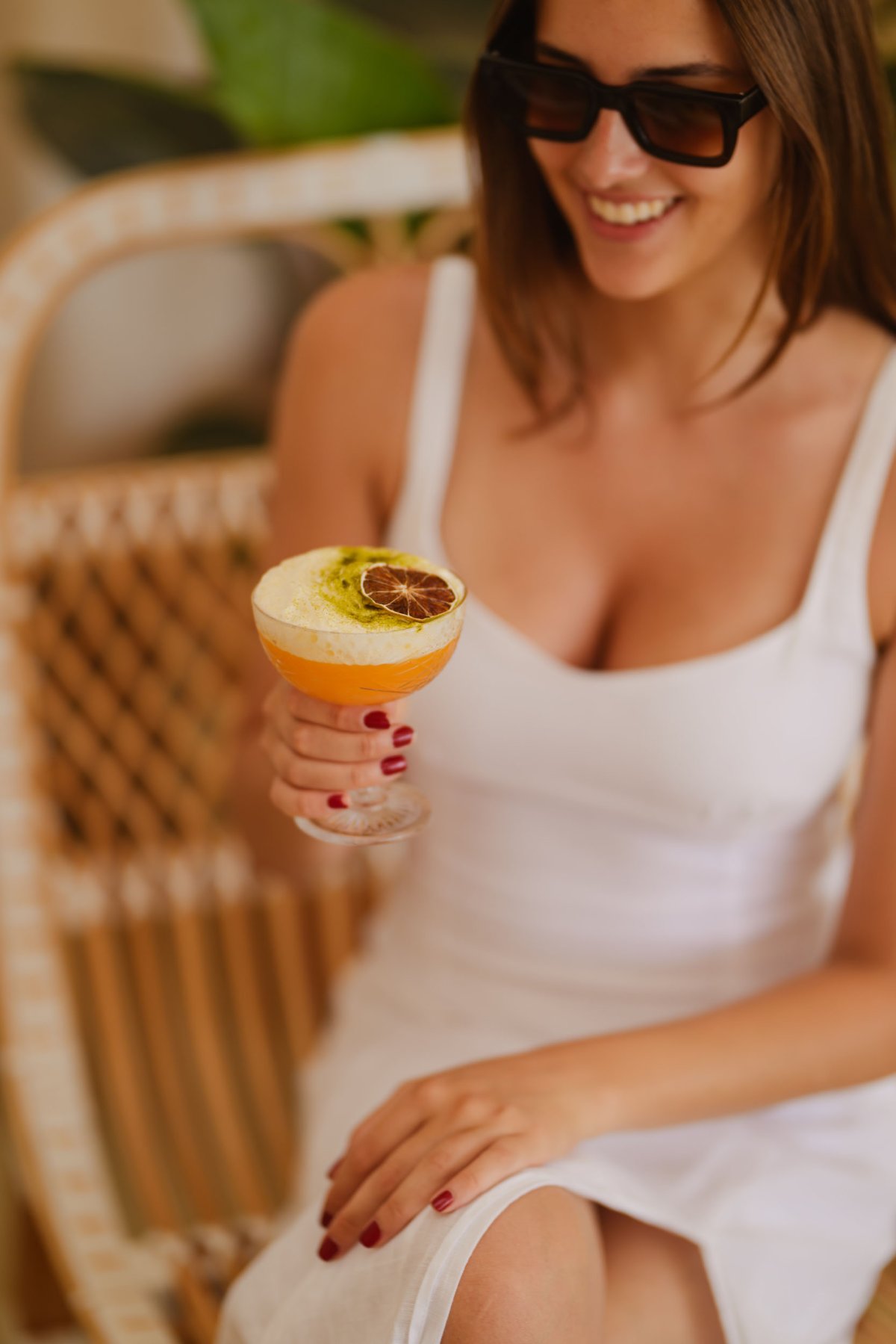 A young lady holding a cocktail, smiling