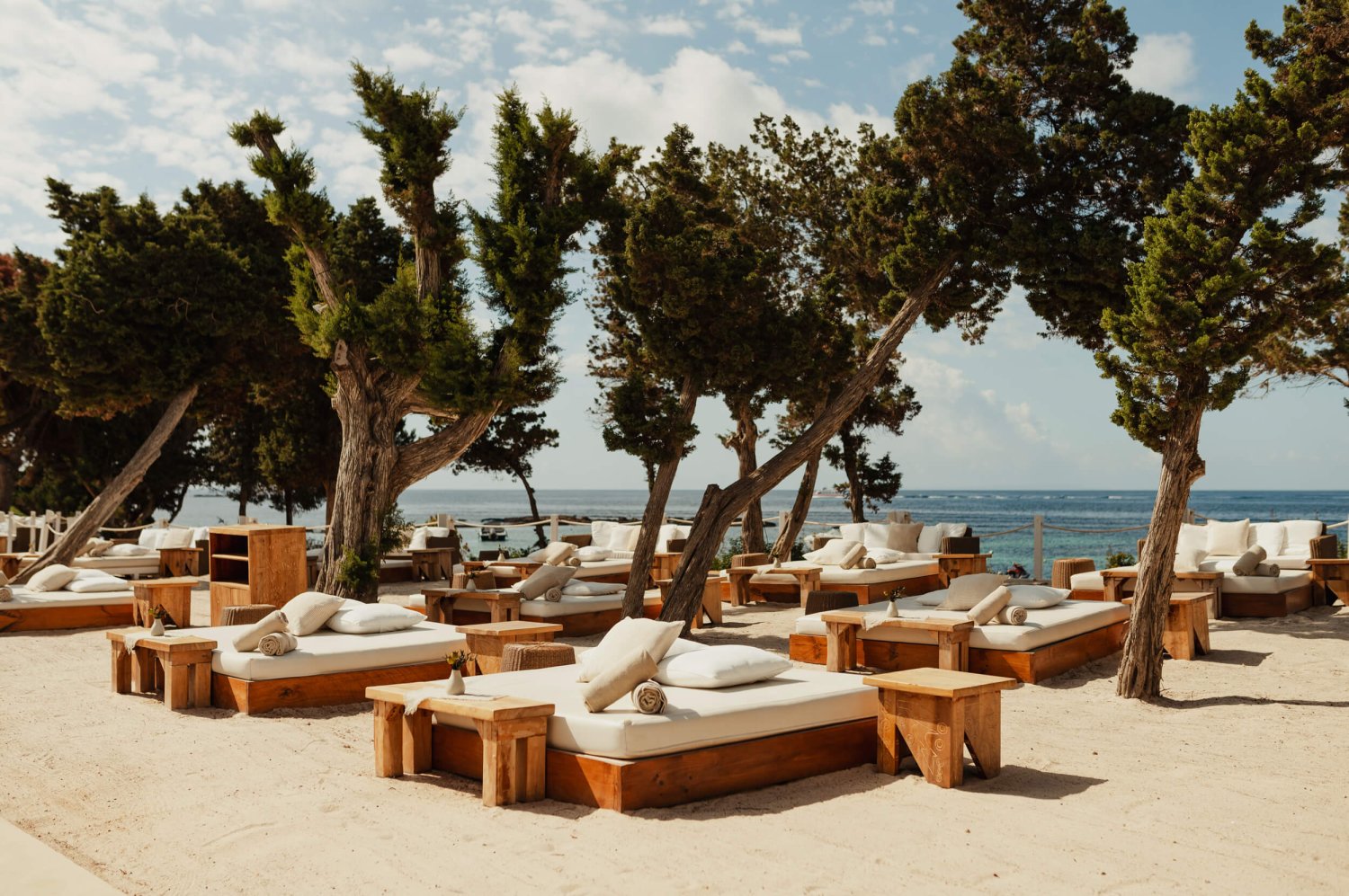 Several sun loungers on a beach wit trees in the background