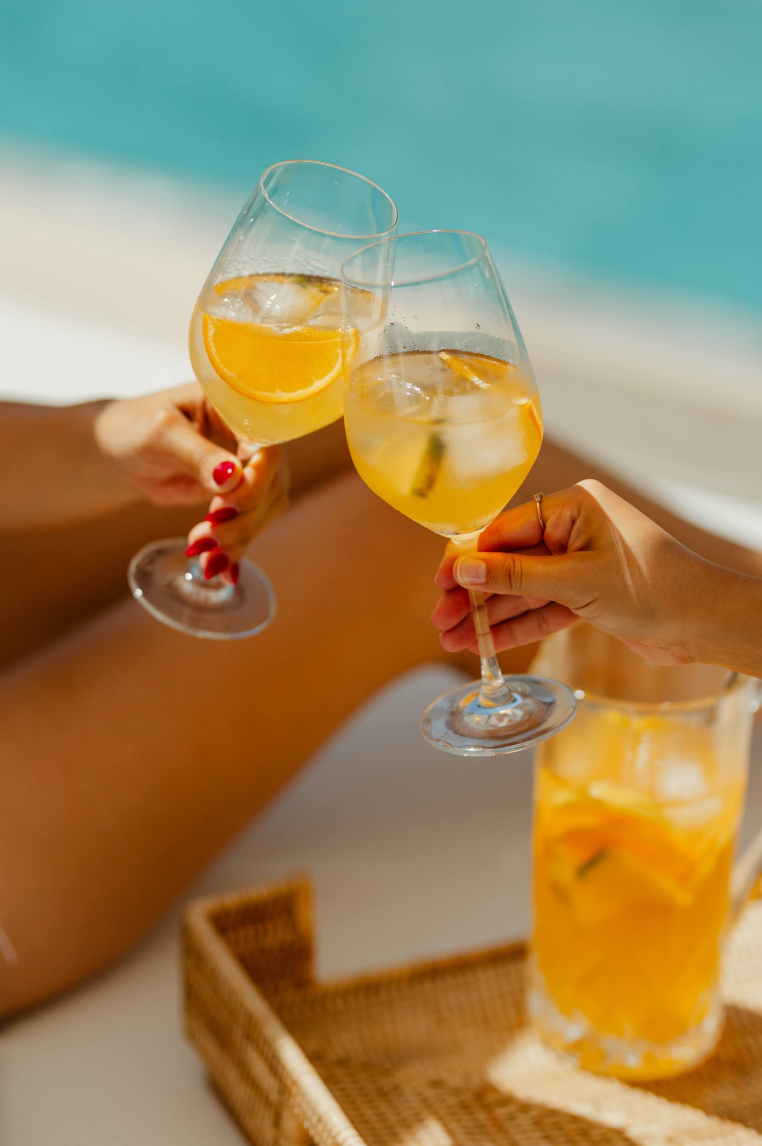 Two ladies tapping glasses of orange in a wine glass together