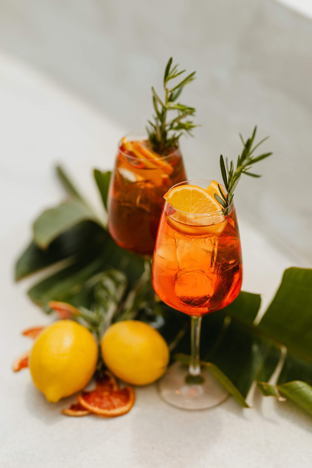 Two Aperol Spritz with lemons and leaves around the glasses