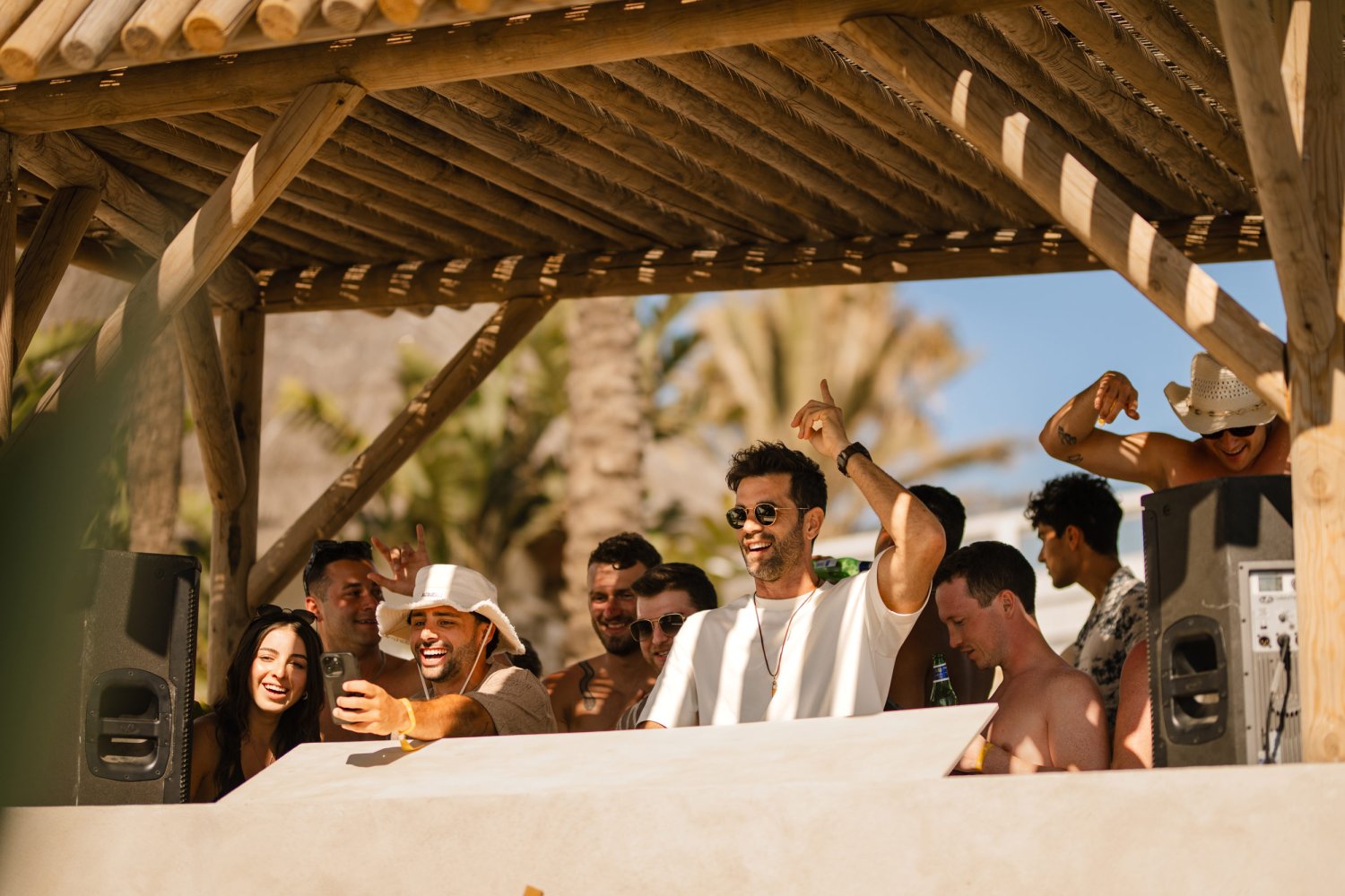 A male DJ dancing and smiling with a crowd of party goers behind