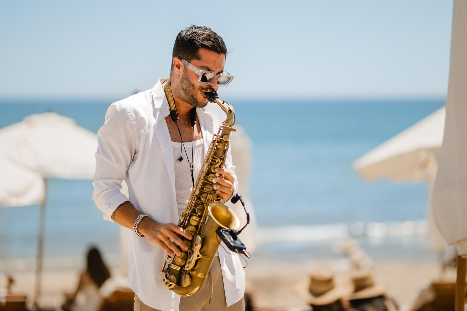 A man playing the Saxophone with the beach in the background