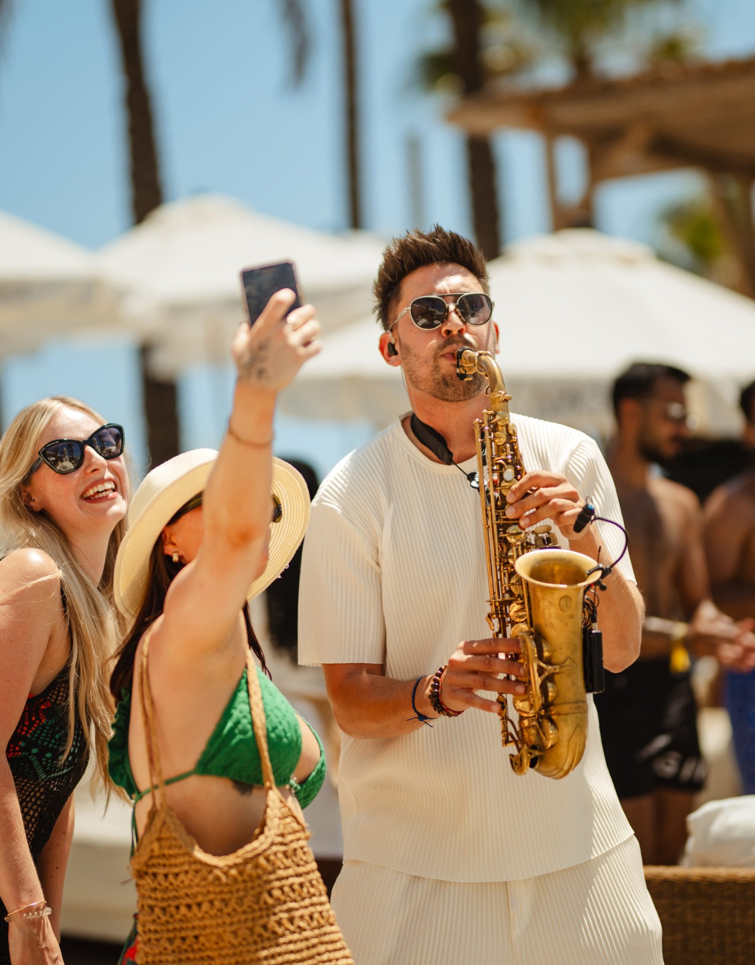 A man playing a saxophone with two girls taking a selfie