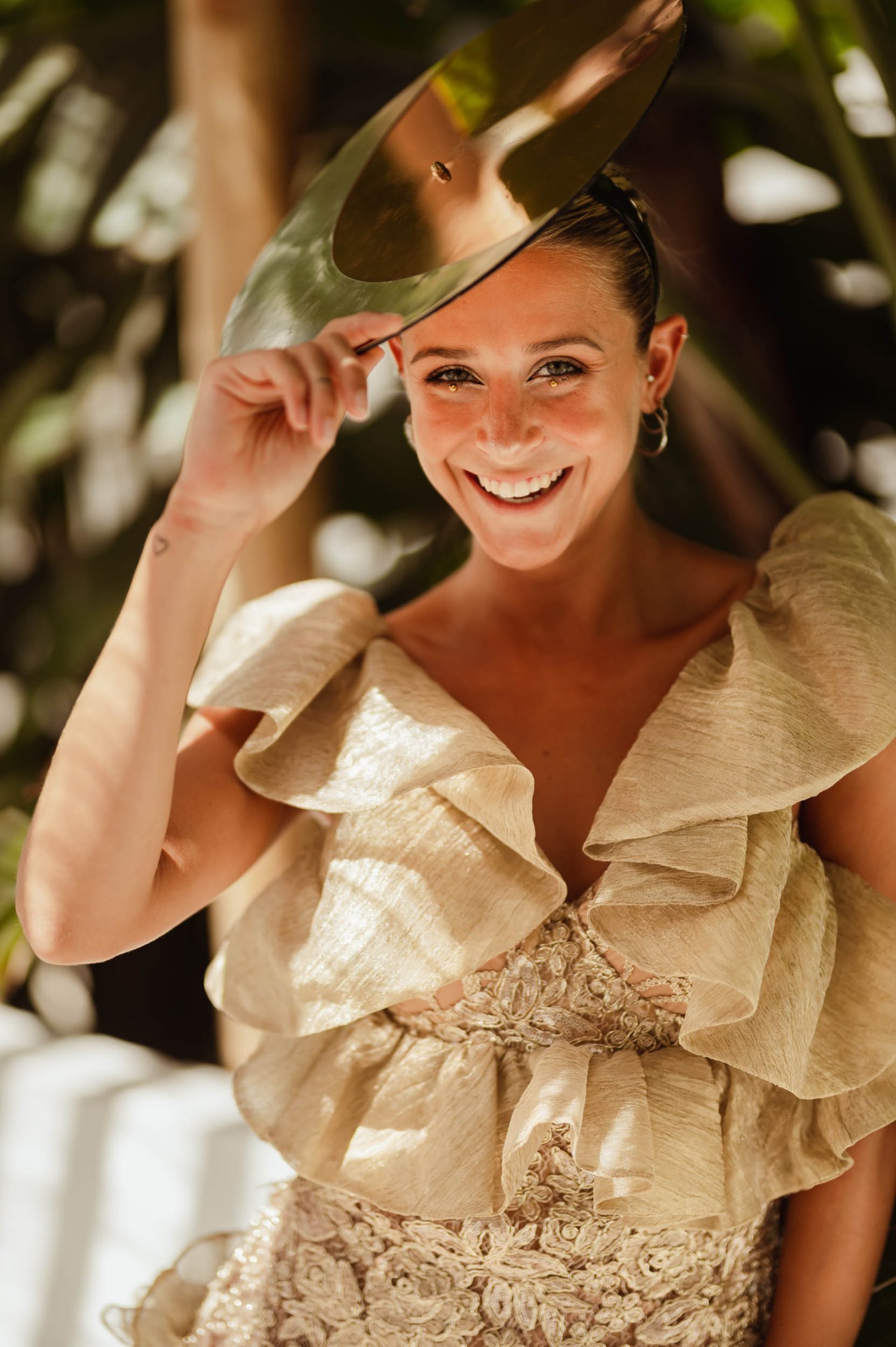 A lady smiling, shielding her face from the sun with a headdress