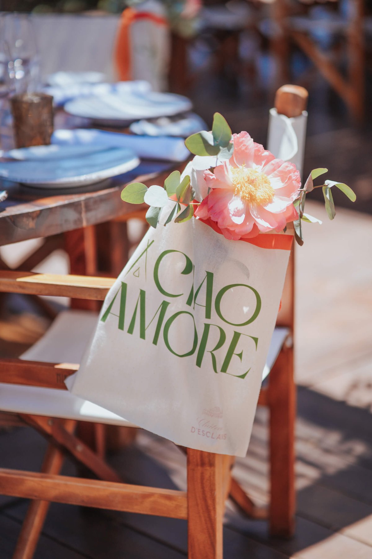 Close up of a bag hanging on a wooden outdoor chair with a flower on top