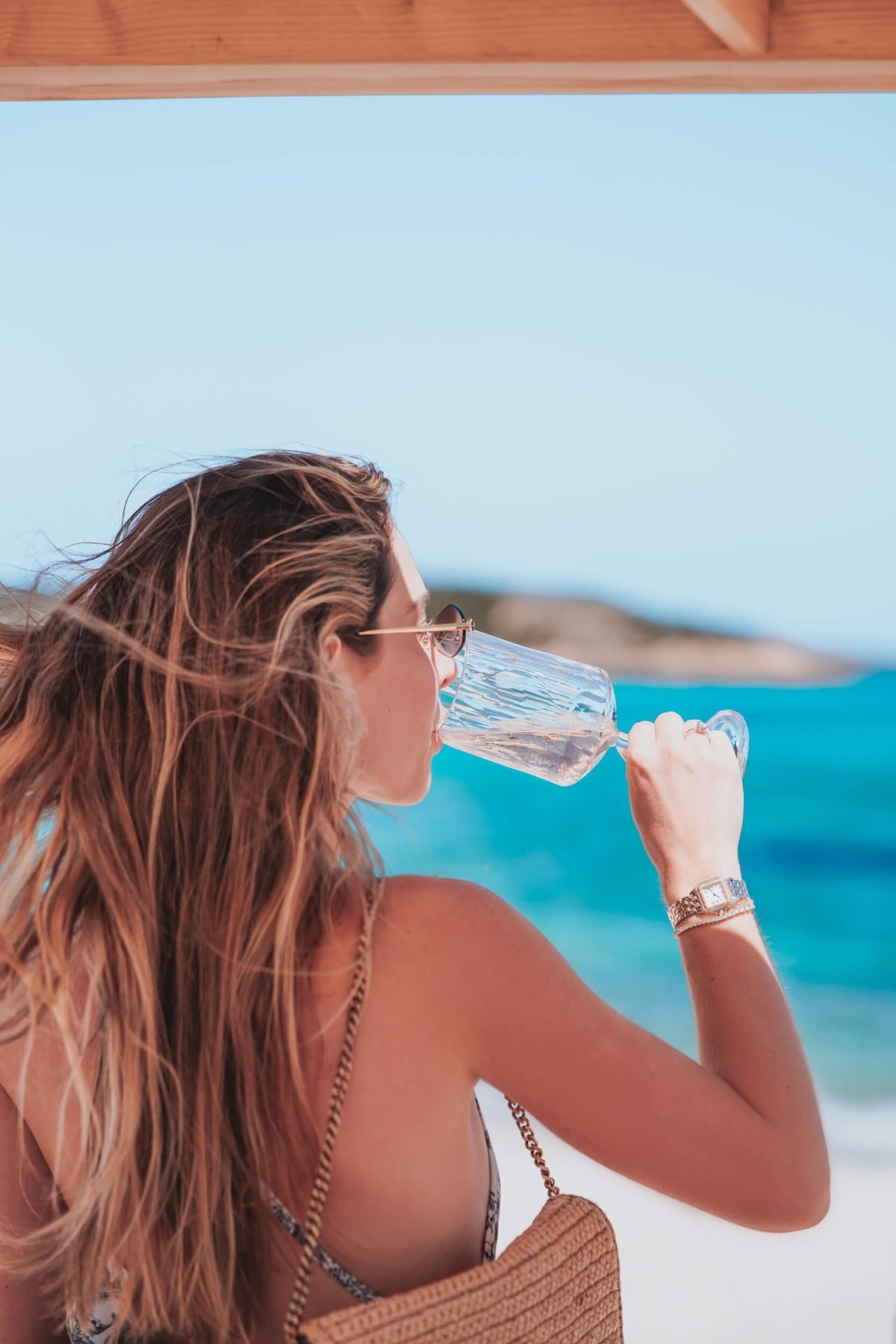 A woman sipping on a wine glass with the sea in the background