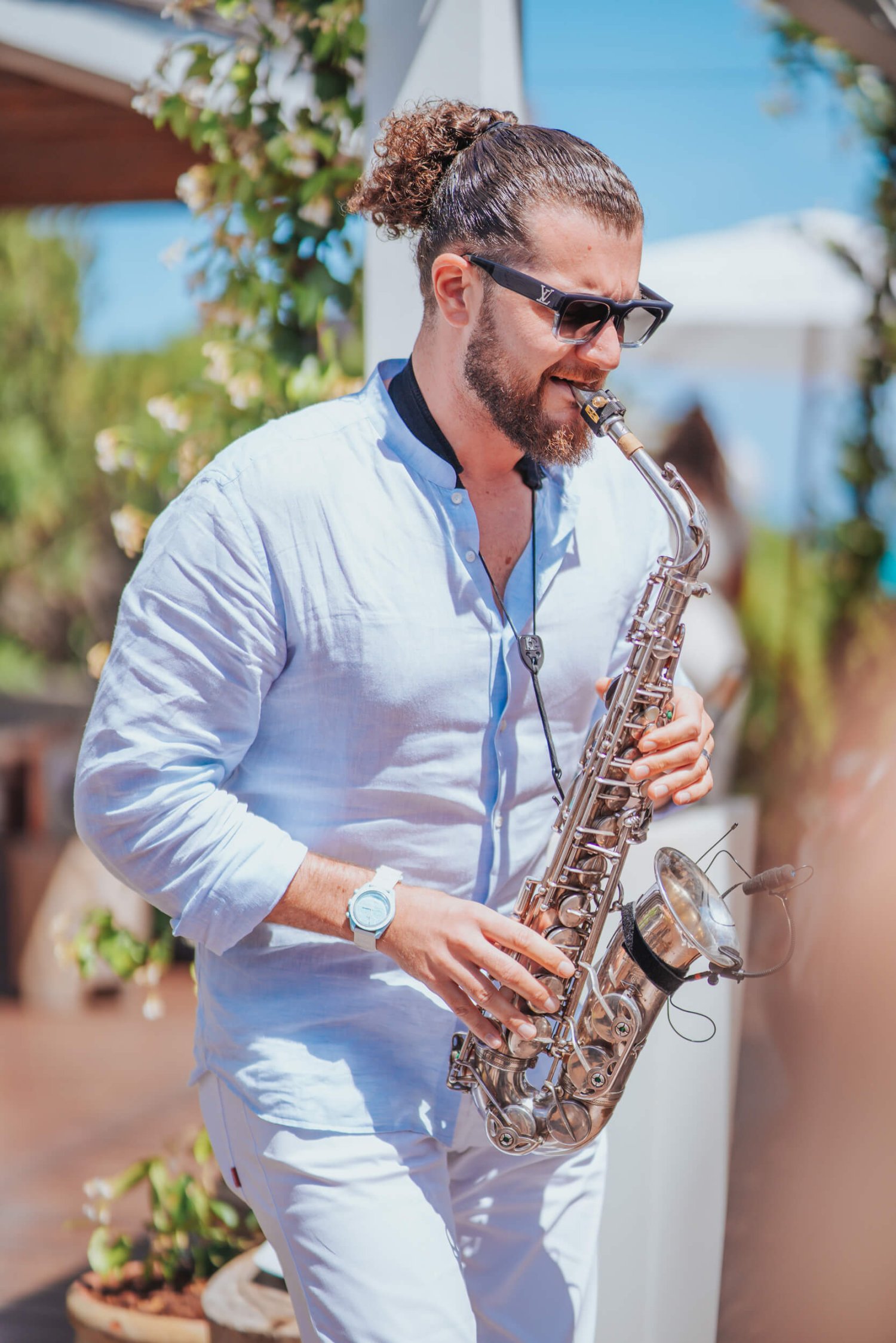 Man in a light blue shirt playing the saxophone