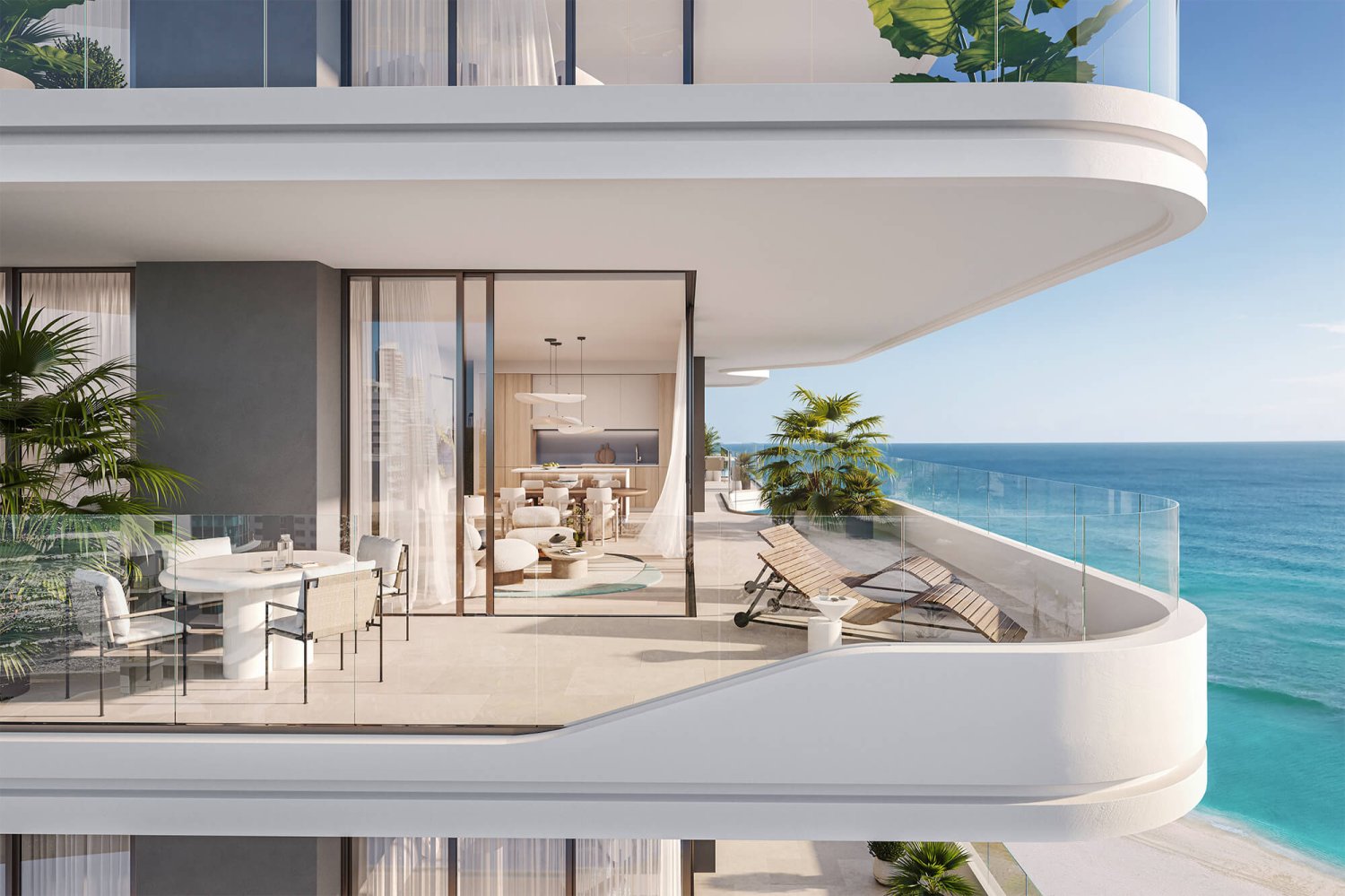 Branded Residences RAK, A balcony looking out to the sea with sun loungers. A floor to ceiling glass door opens through to a minimalistic kitchen-dining area