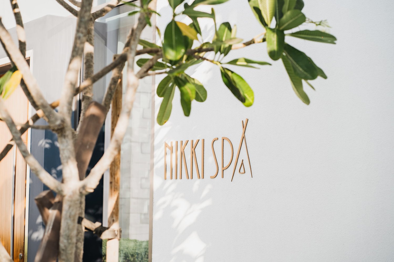 Serene entrance to Nikki Spa featuring a lush tree and a charming sign, beckoning couples for a luxurious Valentine's escape