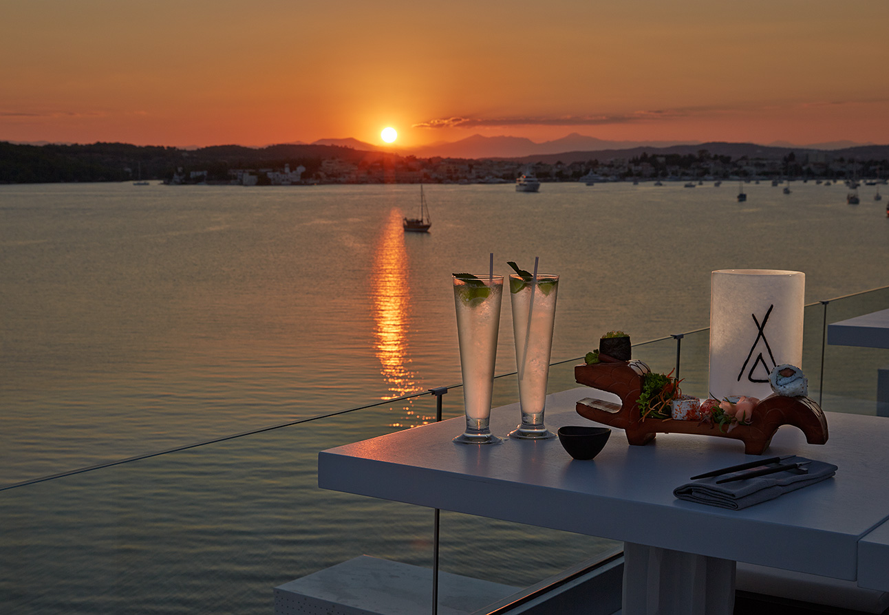 Cocktails on the table with a sunset over the sea behind