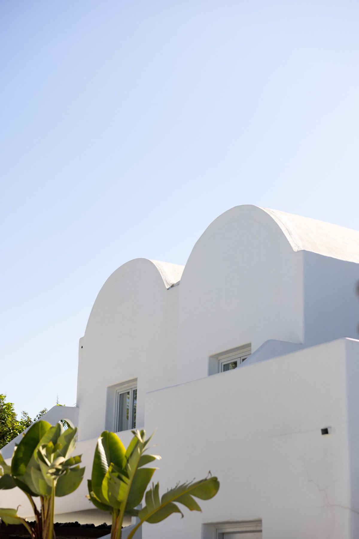 A close-up view of traditional Cycladic architecture featuring smooth, white domed rooftops against a clear blue sky, capturing the serene and iconic aesthetic of Nikki Beach Santorini