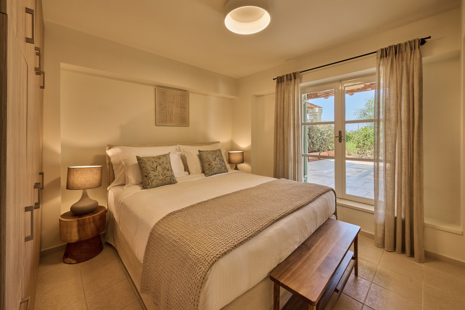 Elegant bedroom featuring a spacious bed and a balcony, inviting guests to unwind in the tranquil Oasis villa