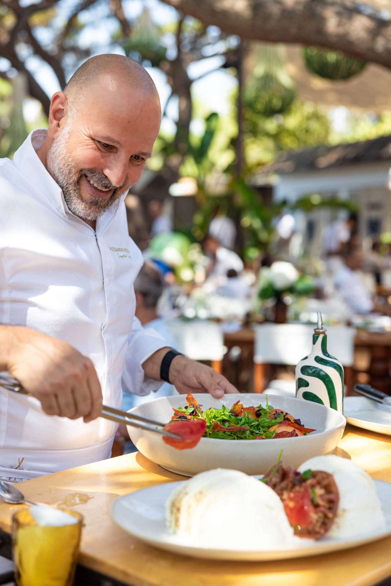Chef smiling placing some garnish on a plate of food