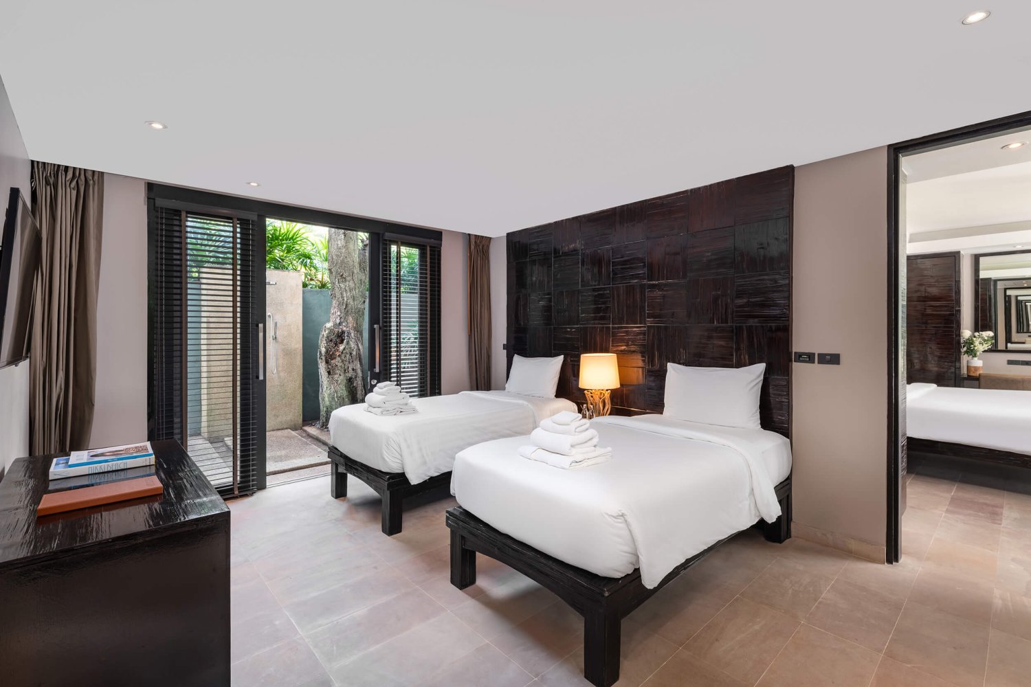 Luxurious bedroom adorned with two comfortable beds and a sliding glass door leading to a tranquil balcony
