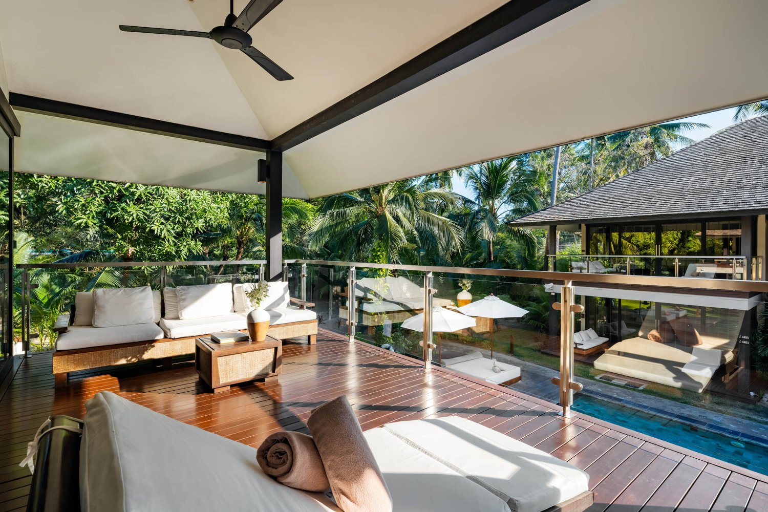 Luxurious balcony featuring plush white couches, overlooking the tranquil expanse of the sparkling pool