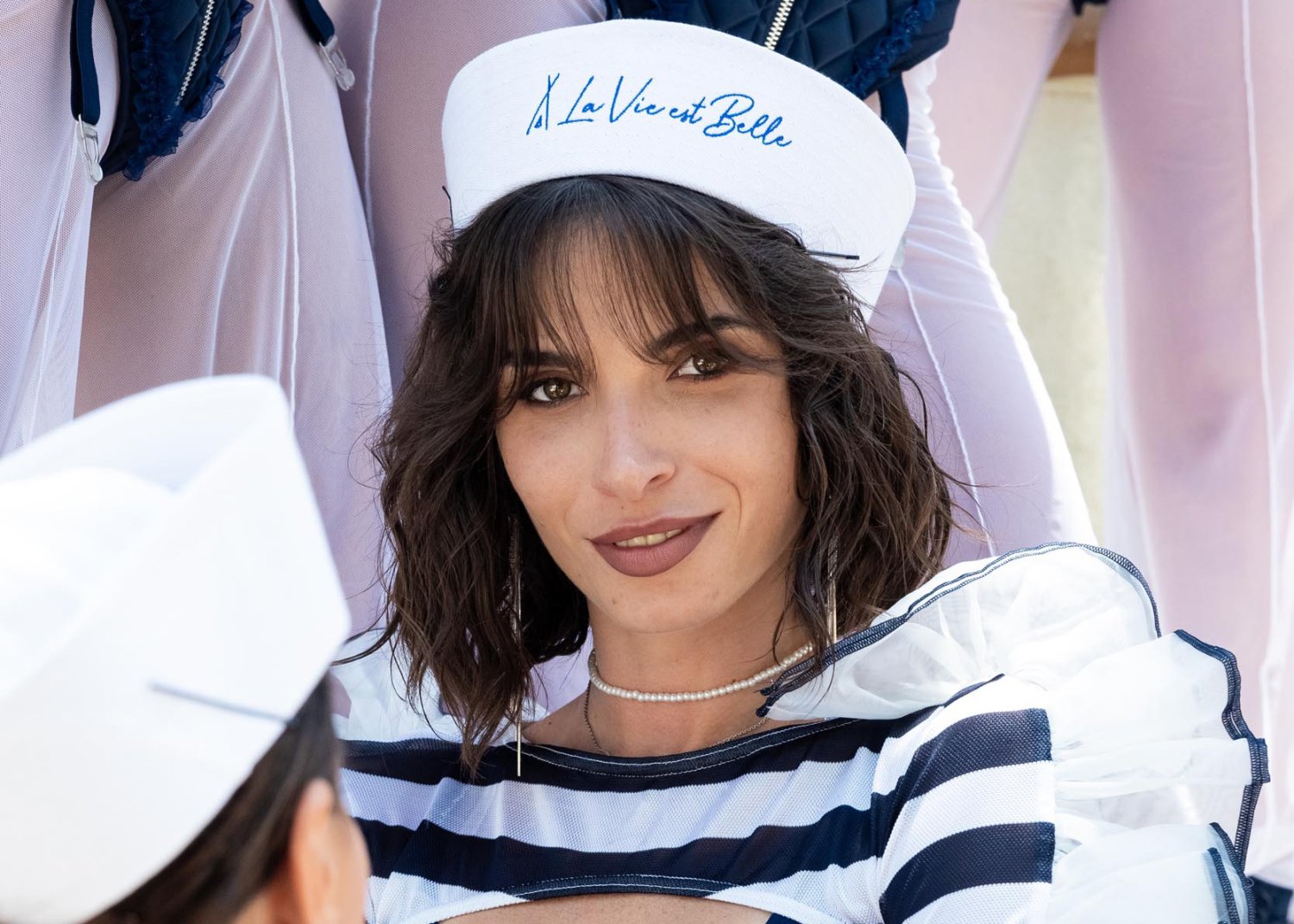 A lady dressed like a Sailor wearing a sailors hat with the words