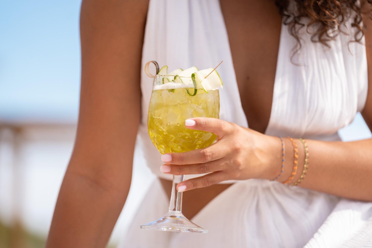 Close up of woman in a white dress holding a cocktail