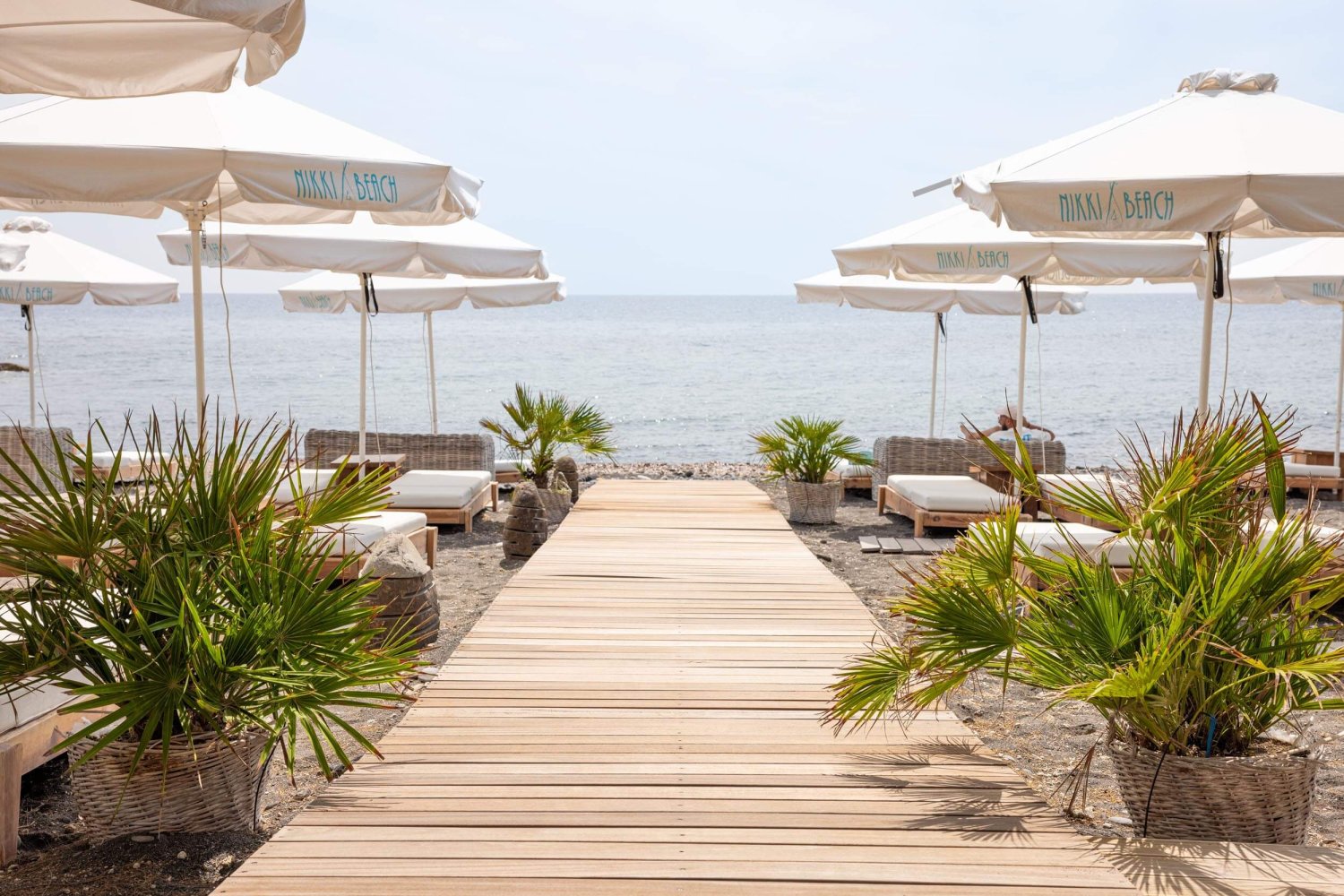 A decked walkway onto the beach with Nikki beach sun beds and umbrellas either side