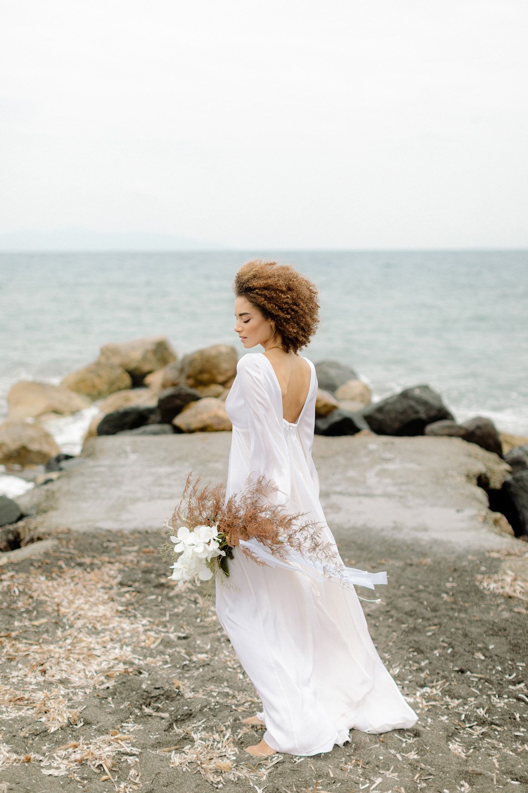 A women in a flowing white wedding dress, holding flowers