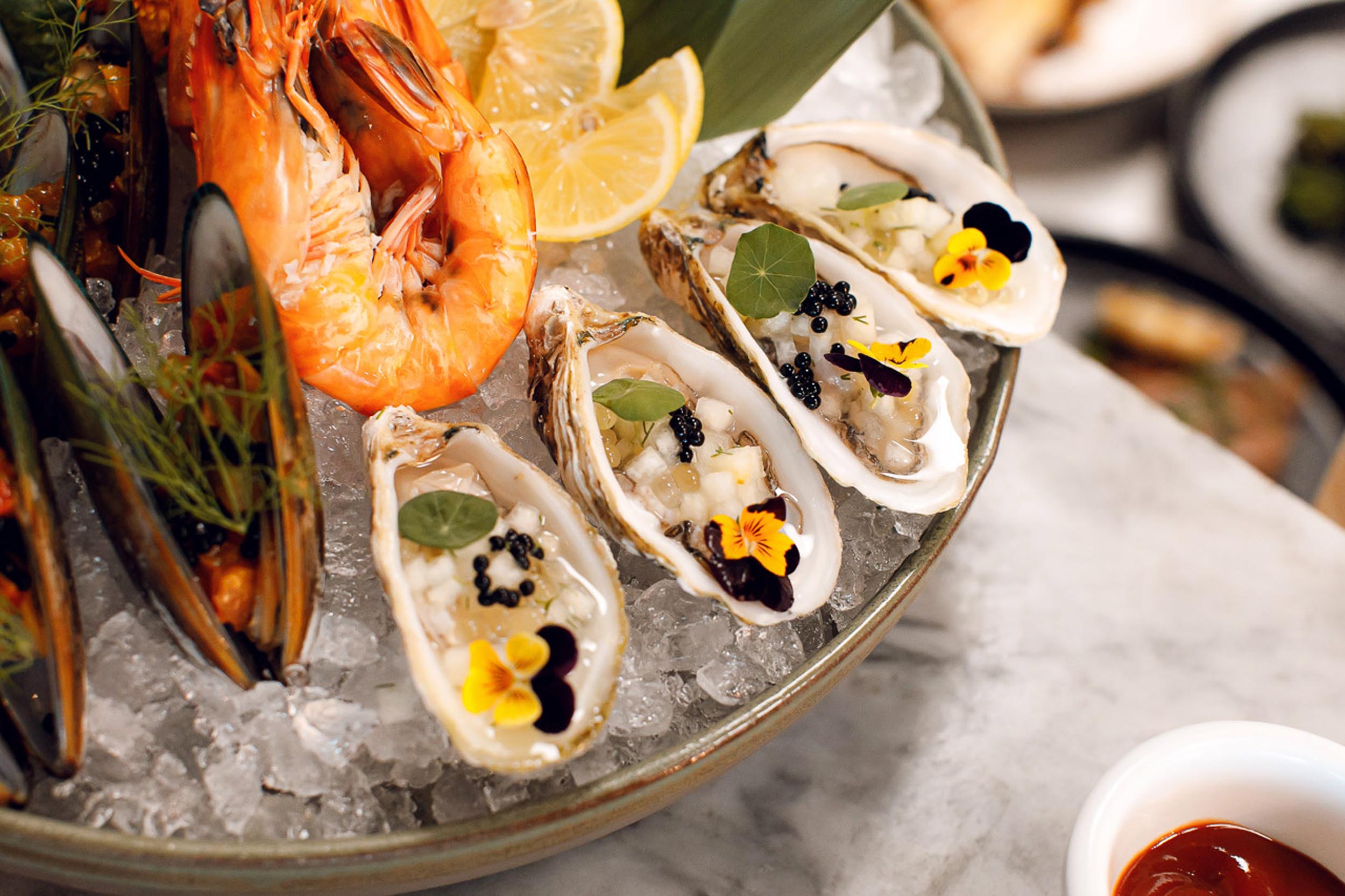 Close up of oysters and lobster sitting on ice