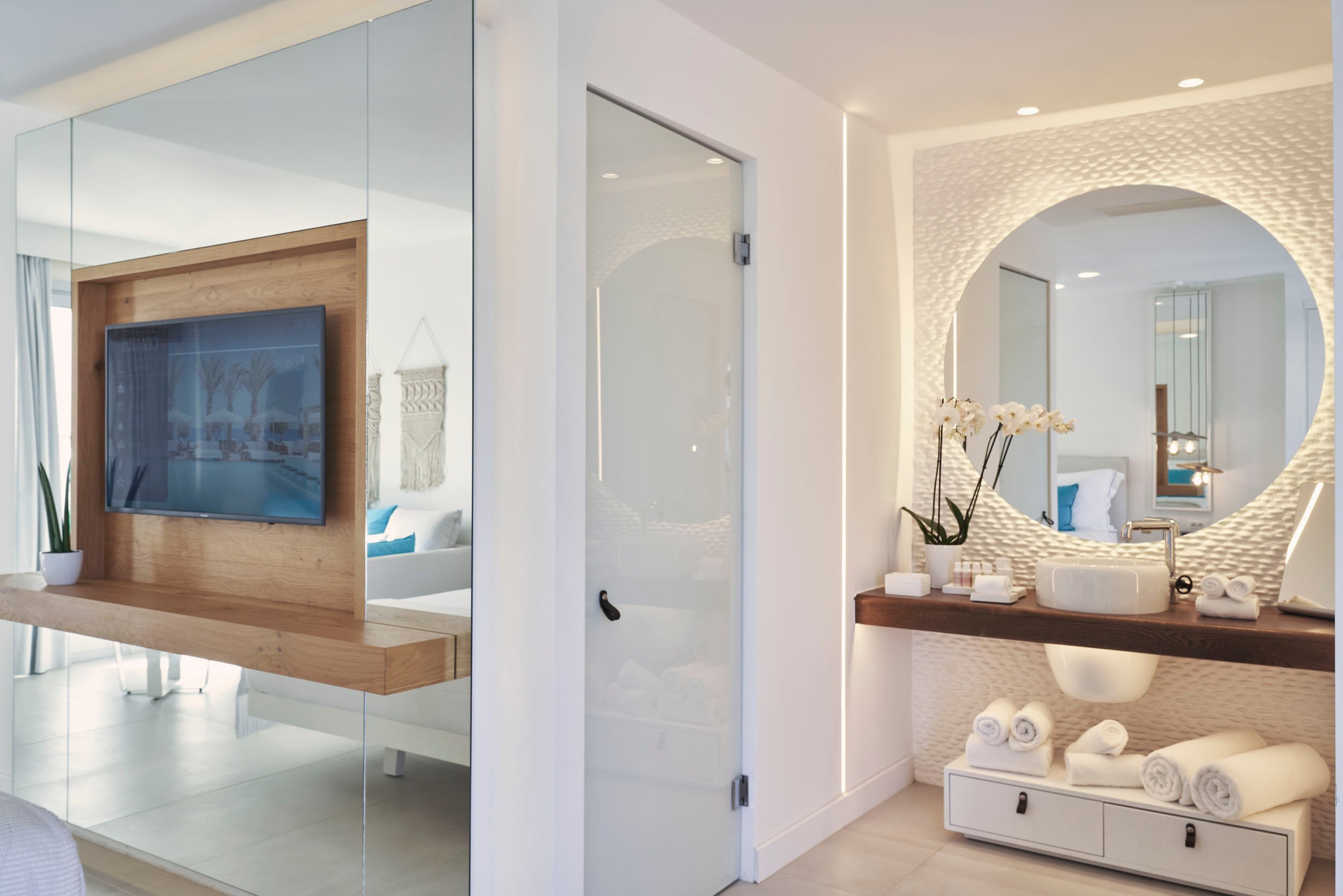 Signature room: (left) wall mounted tv (right) basin and mirror area with towels