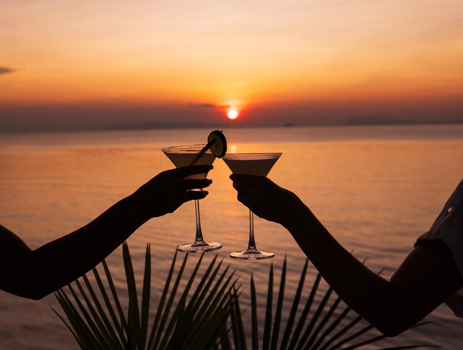 two friends enjoying a cocktail with sunset
