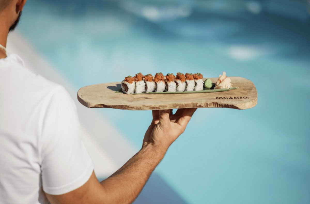 Waiter holding a wooden board of sushi