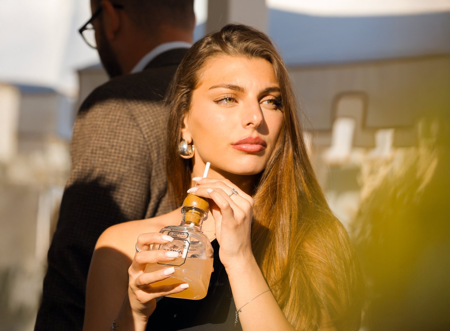 A women drinking a glass of Patron through a straw