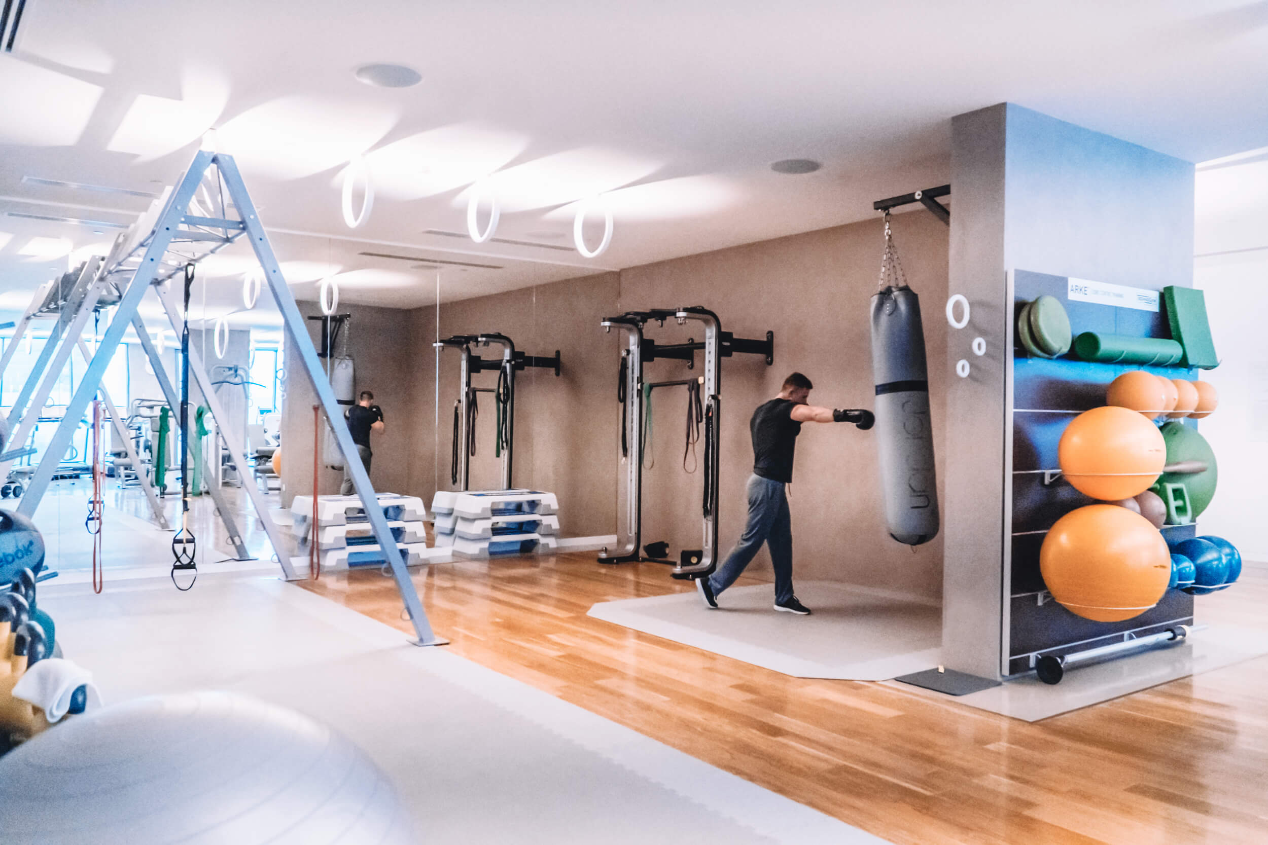 An image of tony gym. A man is punching a punchbag. Gym equipment is seen around the room