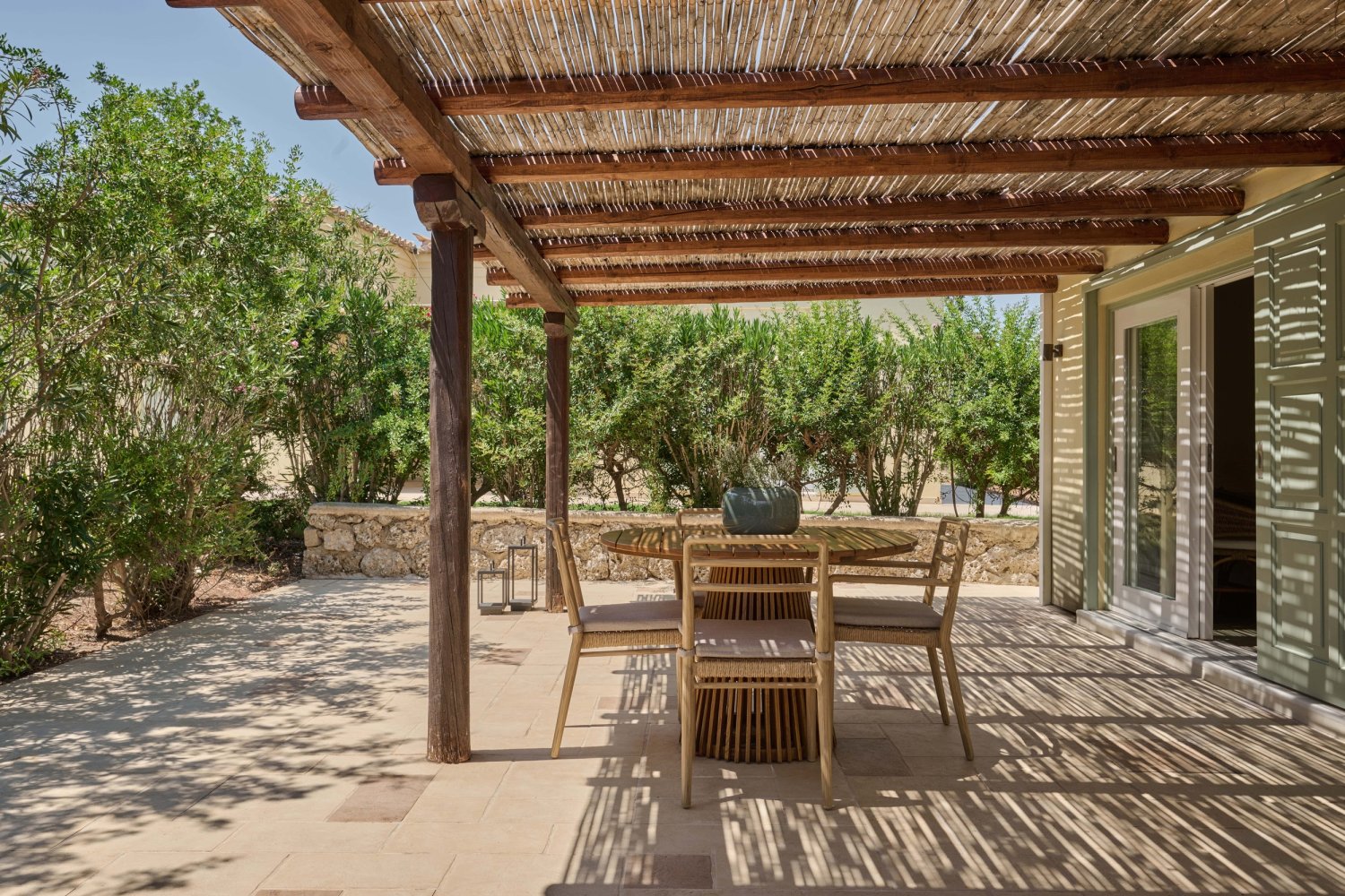 A charming patio with a table and chairs beneath a thatched roof, perfect for enjoying serene seaside moments