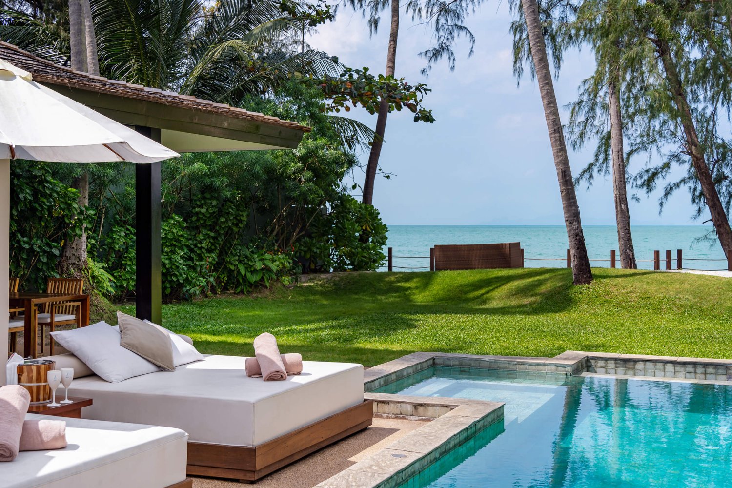 Ultimate beachfront villa with private pool: A pristine white lounge chair and a stylish umbrella beside a shimmering pool, inviting relaxation in a luxurious setting