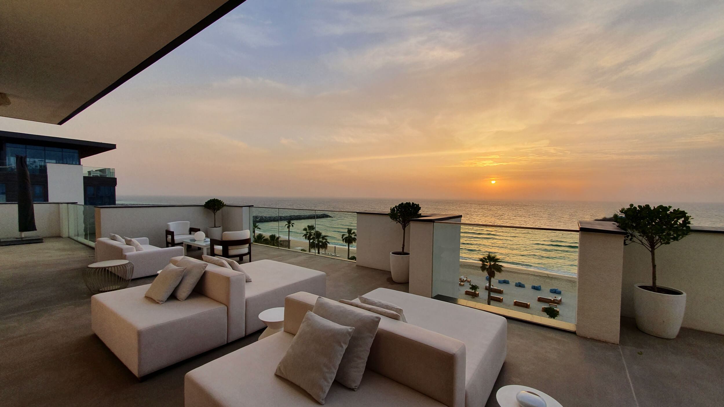 Sunbeds on a balcony, overlooking the beach at sunset