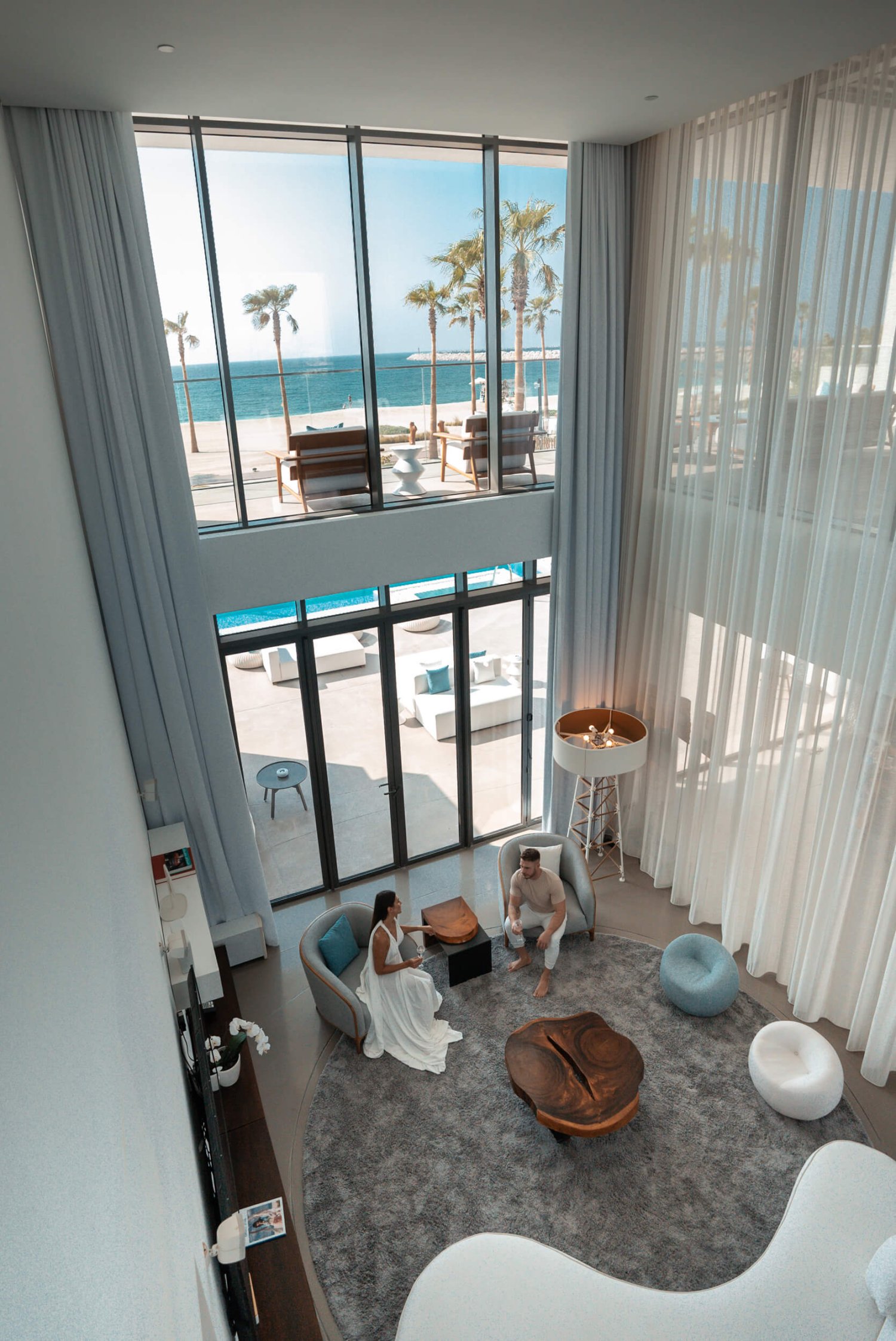 A view from the second floor of the Ultimate villa looking down to the first floor. A man and women are sat chatting in arm chairs