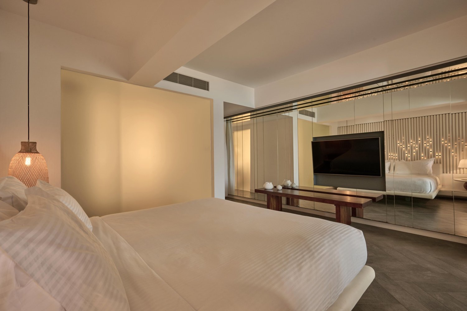 Luxurious hotel room featuring a large bed and a television, designed for comfort and relaxation at Nikki Beach Porto Heli