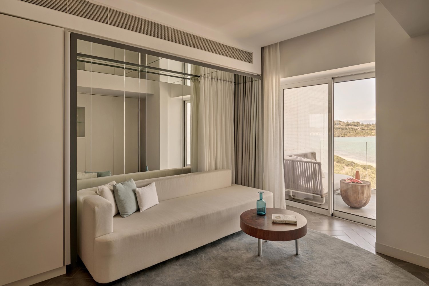 A stylish room featuring a plush couch and a large window with stunning views of the tranquil water outside