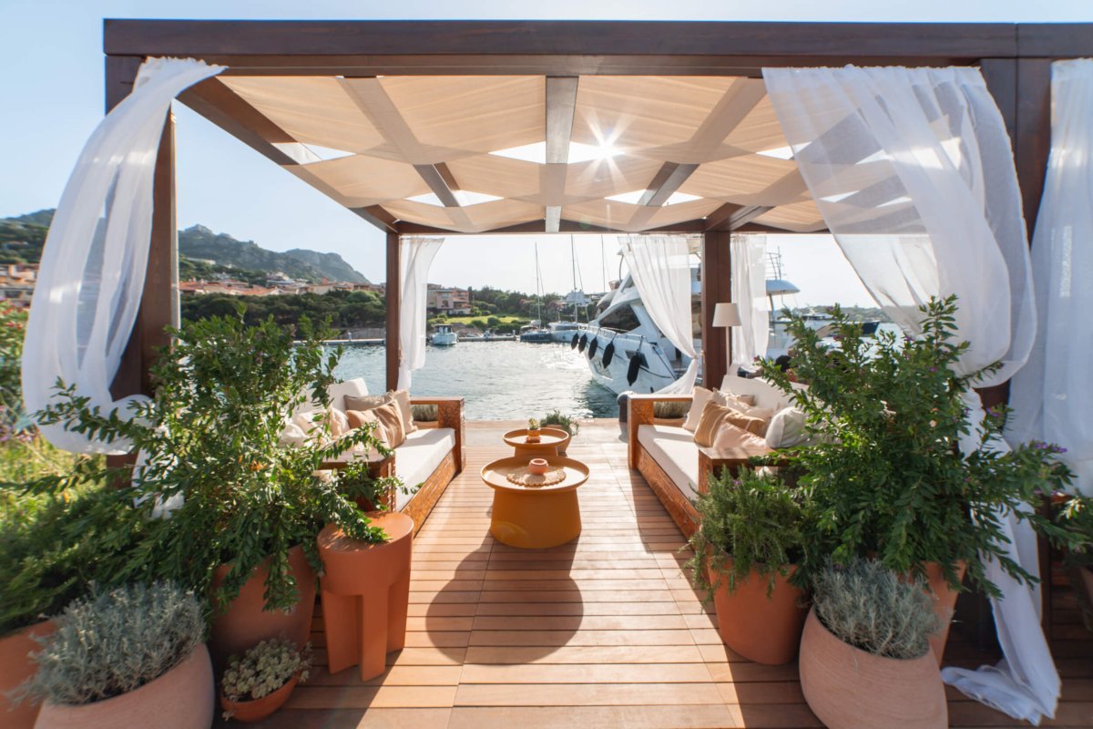 Seating area covered by a pergola next to the harbour surrounded by plants